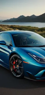 Blue sports car on scenic lakeside road under clear sky.