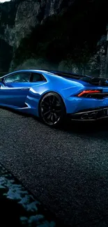 Blue sports car on scenic mountain road.