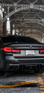 Sleek BMW car under an urban bridge, perfect for mobile wallpaper.