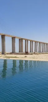 A majestic bridge stretches across tranquil, blue waters under a clear sky.