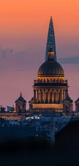 Majestic cityscape with spire at sunset displaying vibrant orange sky hues.