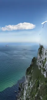 Cliffside view of the ocean with blue sky and white clouds in the background.