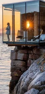 Cliffside glass house overlooking an ocean sunset.