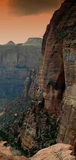 Cliffside view with orange sunset sky and rocky landscape.