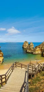 Wooden walkway leading to a scenic beach with blue sky, ocean, and cliffs.