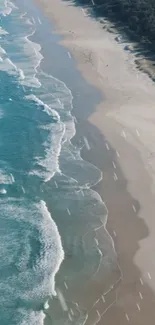 Aerial view of turquoise ocean waves meeting sandy beach under a clear sky.