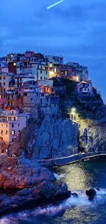 Stunning coastal village at dusk with illuminated buildings and deep blue sea.