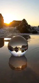 Sunset reflected in a glass sphere on a calm beach, creating a tranquil mobile wallpaper.