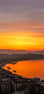 Vivid orange coastal sunset with beach and mountain silhouette.