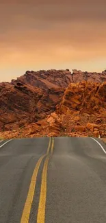 Desert road leading through rocky terrain with an orange sky.