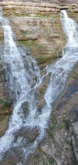 Double waterfall cascading over rocky cliffs with surrounding greenery.