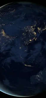 Earth at night with city lights visible from space, dark blue cosmic background.