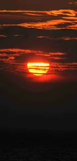 Fiery sunset with red and orange glow against dark clouds in a bold scenic view.