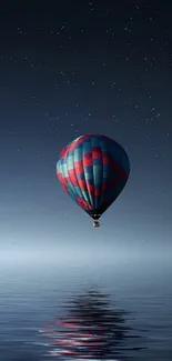 A hot air balloon against a starry night sky reflecting on calm water.