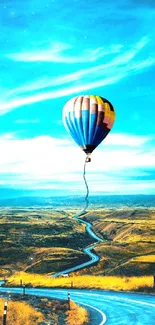 Hot air balloon over a winding road with a vibrant blue sky.