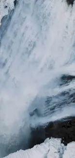 Icy waterfall cascading down rocks with snowy surroundings.