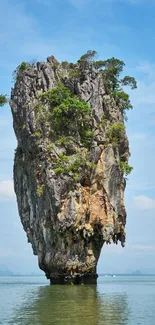 Towering island rock formation over tranquil blue waters.