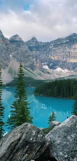 Turquoise mountain lake with pine trees and rocky foreground.