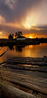 Lakeside sunset with orange sky and wooden dock in tranquil setting.