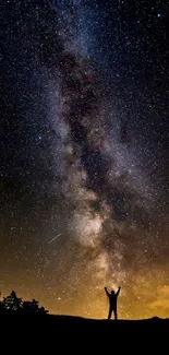 Silhouette under starry night sky with Milky Way galaxy.