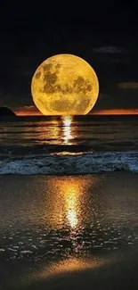 Golden moon reflecting on a tranquil beach at night.