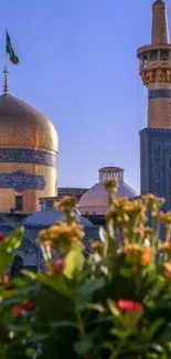 Golden domed mosque with flowers and clear blue sky.