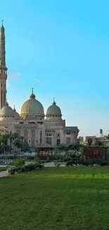 Majestic mosque with green field under clear blue sky wallpaper.