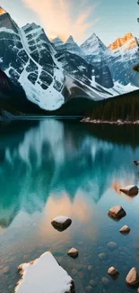 Scenic mountain lake with teal water reflection and snow-capped peaks at sunset.