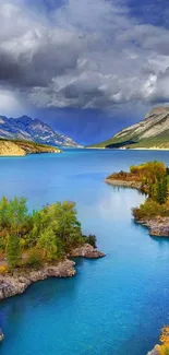 A clear blue lake with mountains and autumn trees.