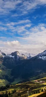 Snowy mountains under a blue sky and lush green valleys.