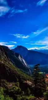 Nightscape with blue sky over mountains and lush green valley.