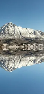 Snowy mountain perfectly reflected in a calm lake under a clear blue sky.