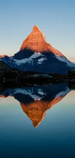 Mountain reflecting in calm water at sunrise.