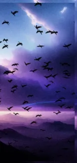 Purple sunset sky with flock of birds over mountains.