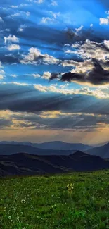 Vibrant sunset over mountains with blue sky and rays through clouds.