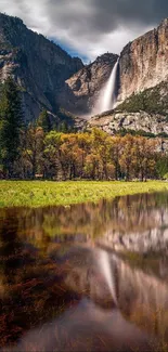 Majestic mountain waterfall reflected in calm waters under a cloudy sky.