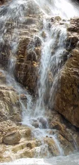 Mountain waterfall with lush greenery and rocky terrain.