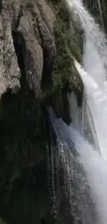 Breathtaking waterfall cascading down rugged rocks in nature wallpaper.