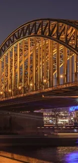 Illuminated bridge at night with water reflection.