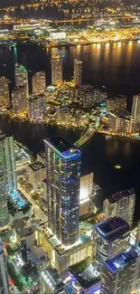 Aerial night cityscape with glowing high-rise buildings and vibrant city lights.