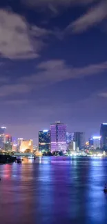 Night cityscape with buildings and river reflections in vibrant colors.