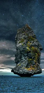 Towering sea rock with starry night sky, perfect mobile wallpaper.