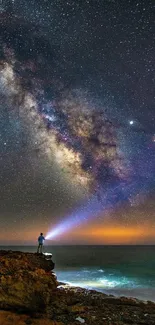 Person with flashlight under vibrant star-filled night sky and Milky Way.