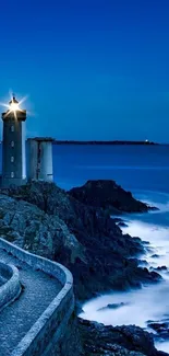 Lighthouse glowing at night overlooking a vast deep blue ocean.