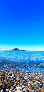 Ocean view with pebbled beach and clear blue sky.