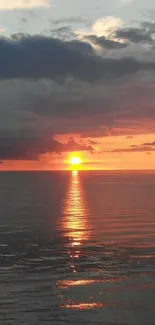 Sunset over calm ocean with orange hues.