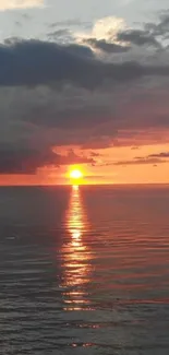 Sunset over ocean with vibrant orange sky.