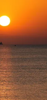 Tranquil ocean sunset with vibrant orange sky.