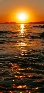 Tranquil ocean sunset with warm orange hues reflecting on water.