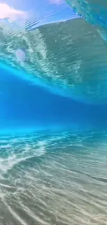 Underwater view of ocean waves with sunlight filtering through clear blue waters.